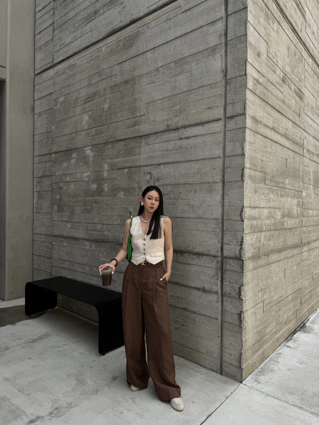 Brown trouser styling against a textured concrete wall