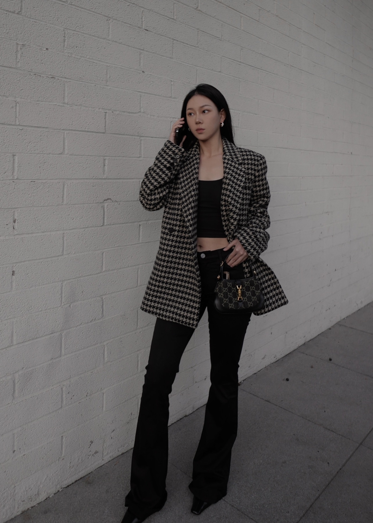 Houndstooth coat styling against a white wall
