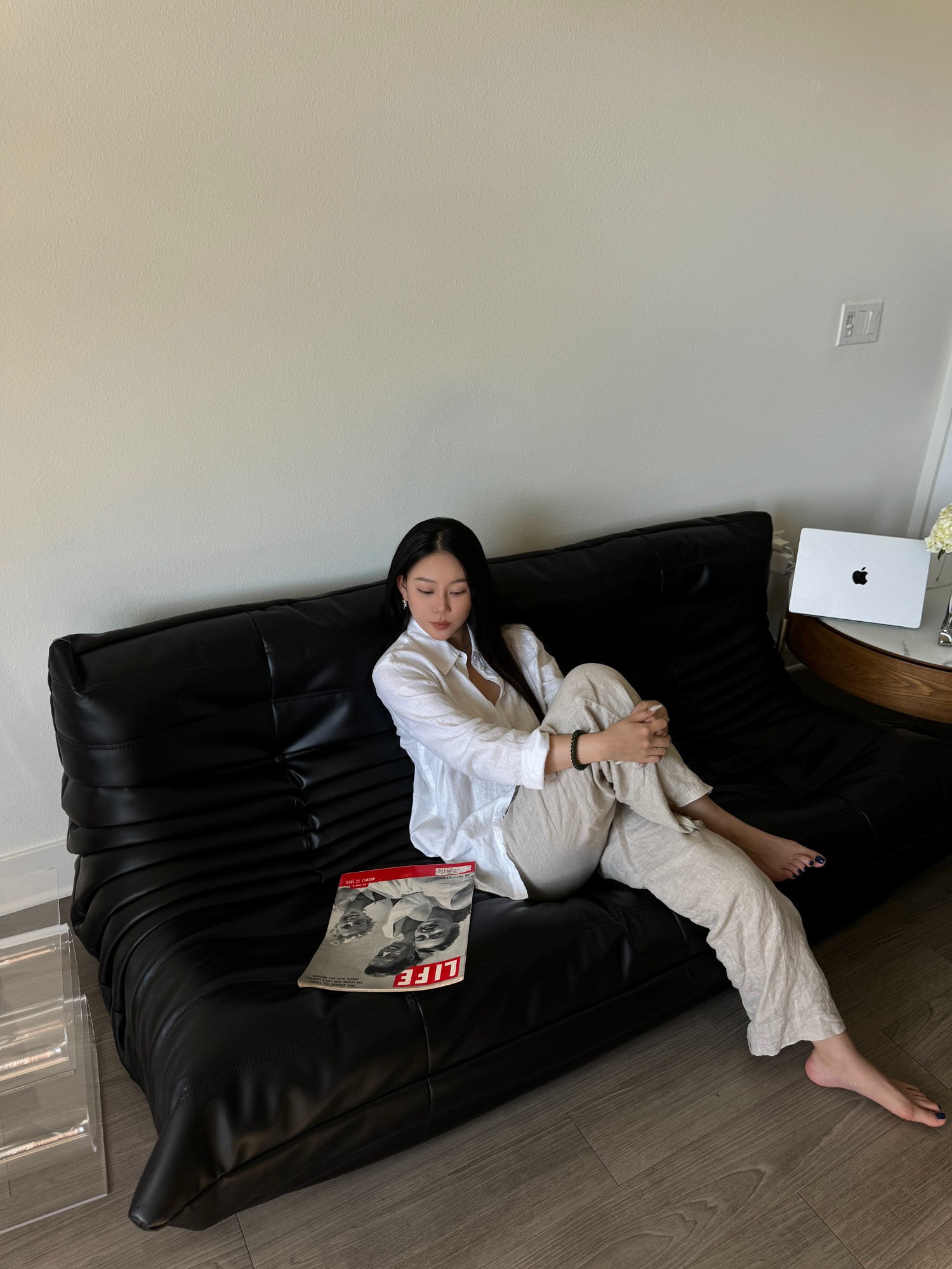 White linen shirt and trousers reclining on a black sofa