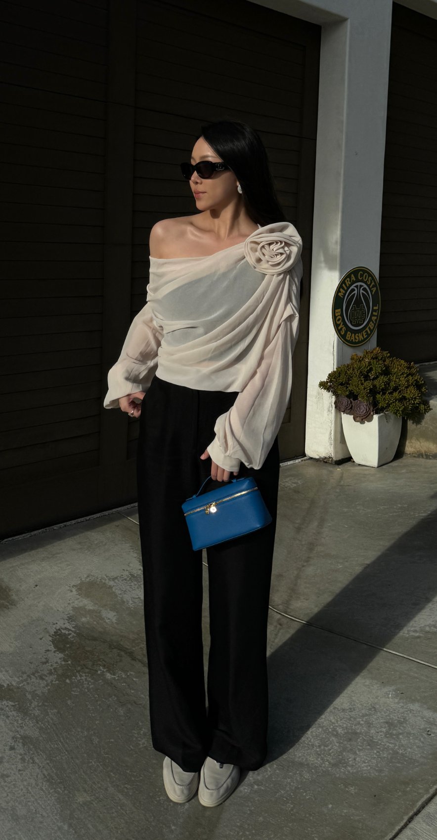 Commense off-shoulder rosette top styled in profile against a sunlit garage wall