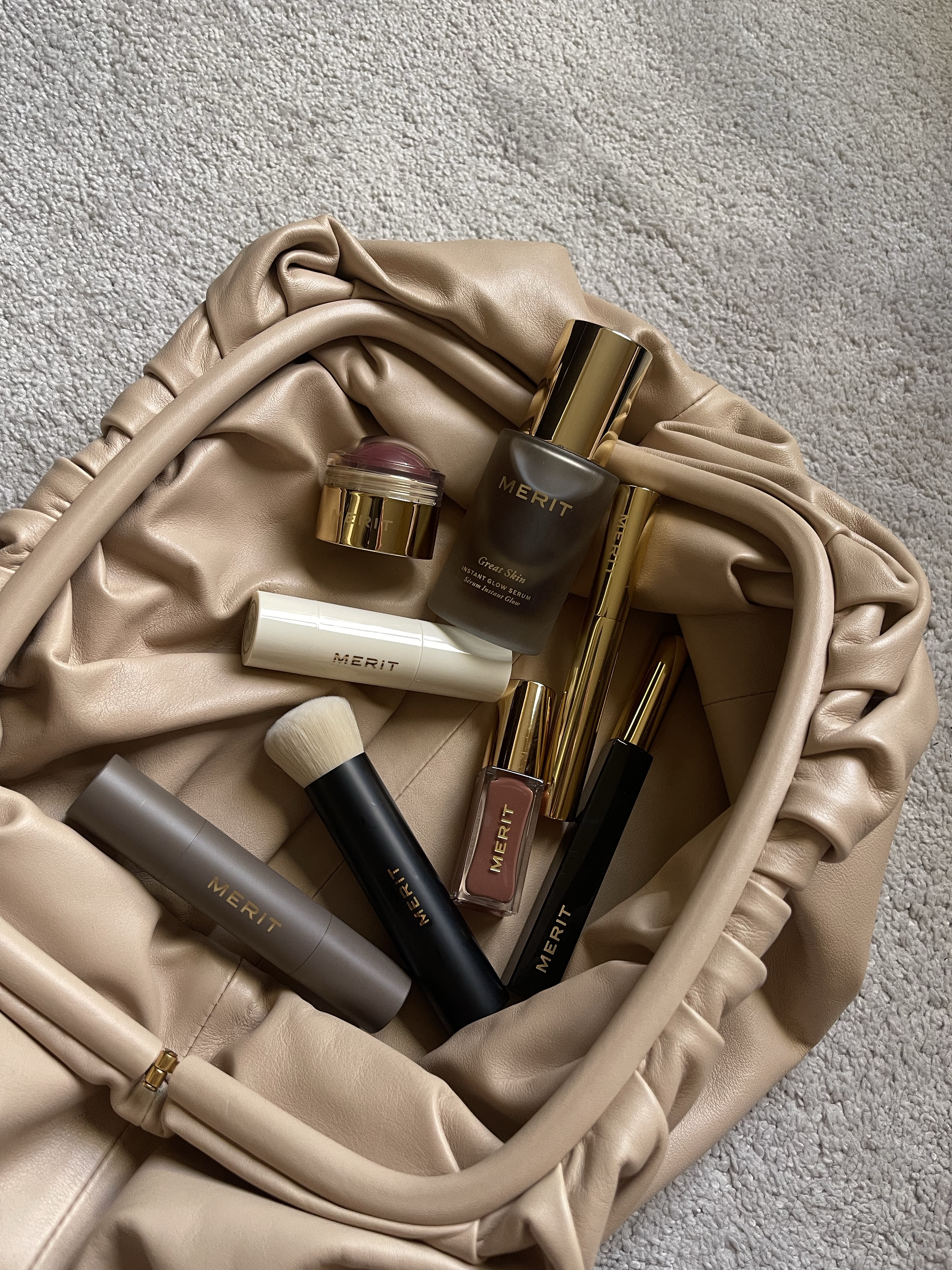 Merit beauty products in a nude leather pouch