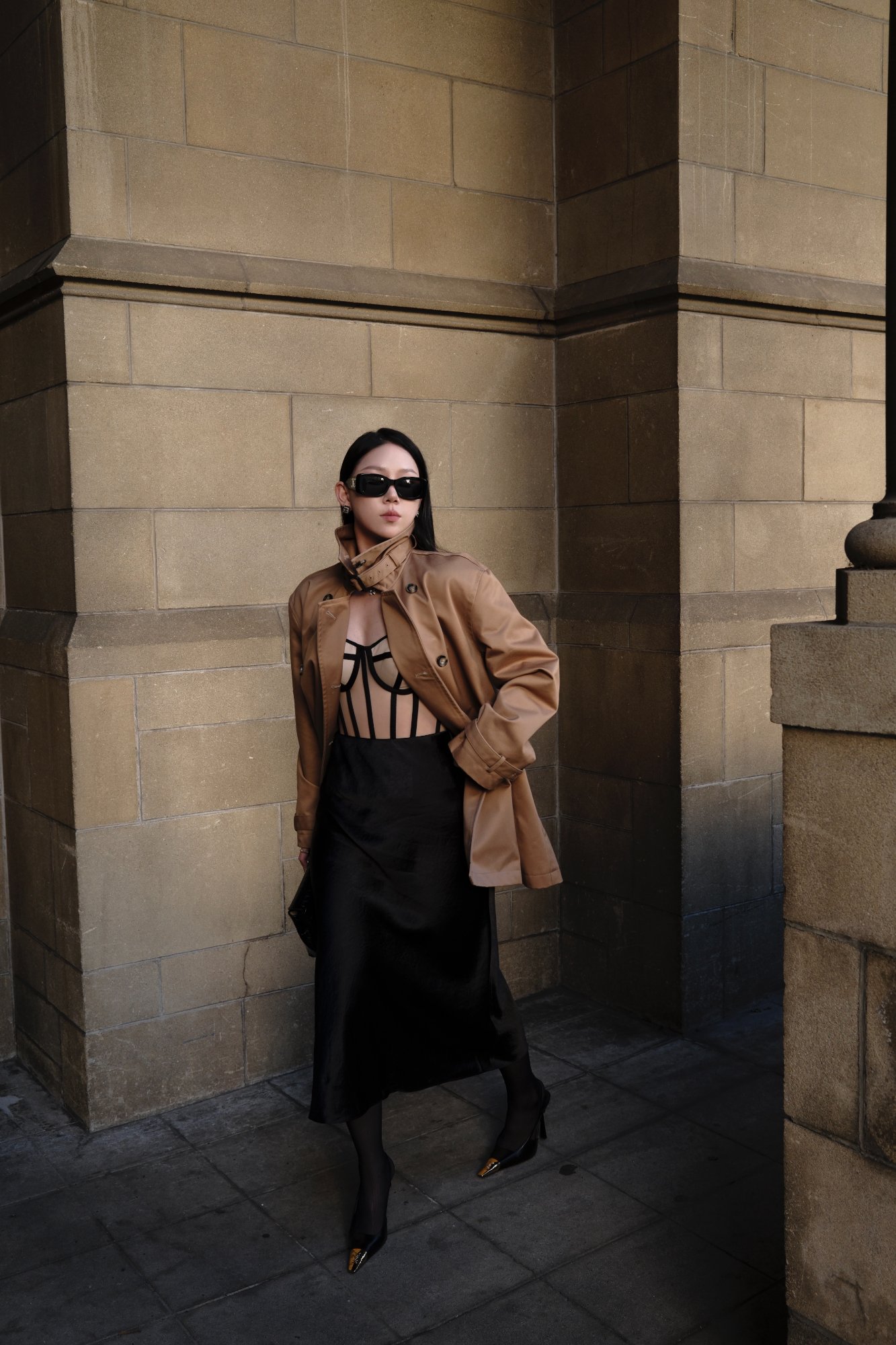 Perfect Corset boned bodice worn under a camel trench against sandstone architecture