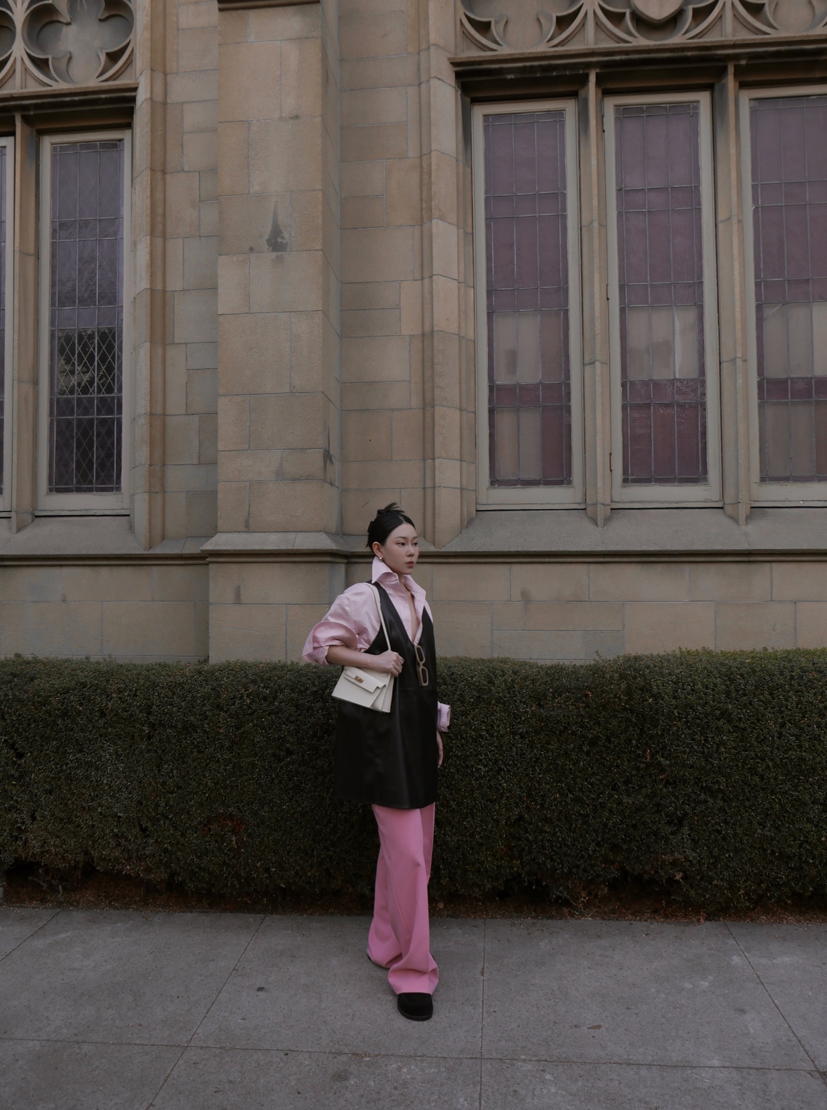 Pink shirt and black leather dress against architecture