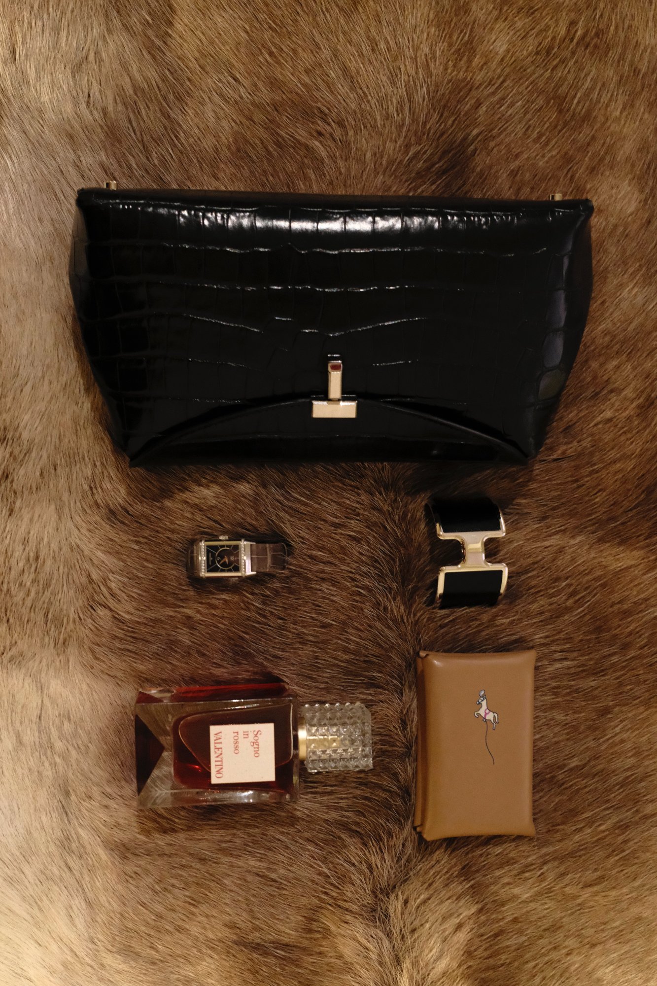 Valentino Sogno in rosso fragrance with a black croc clutch and Hermès cuff on fur