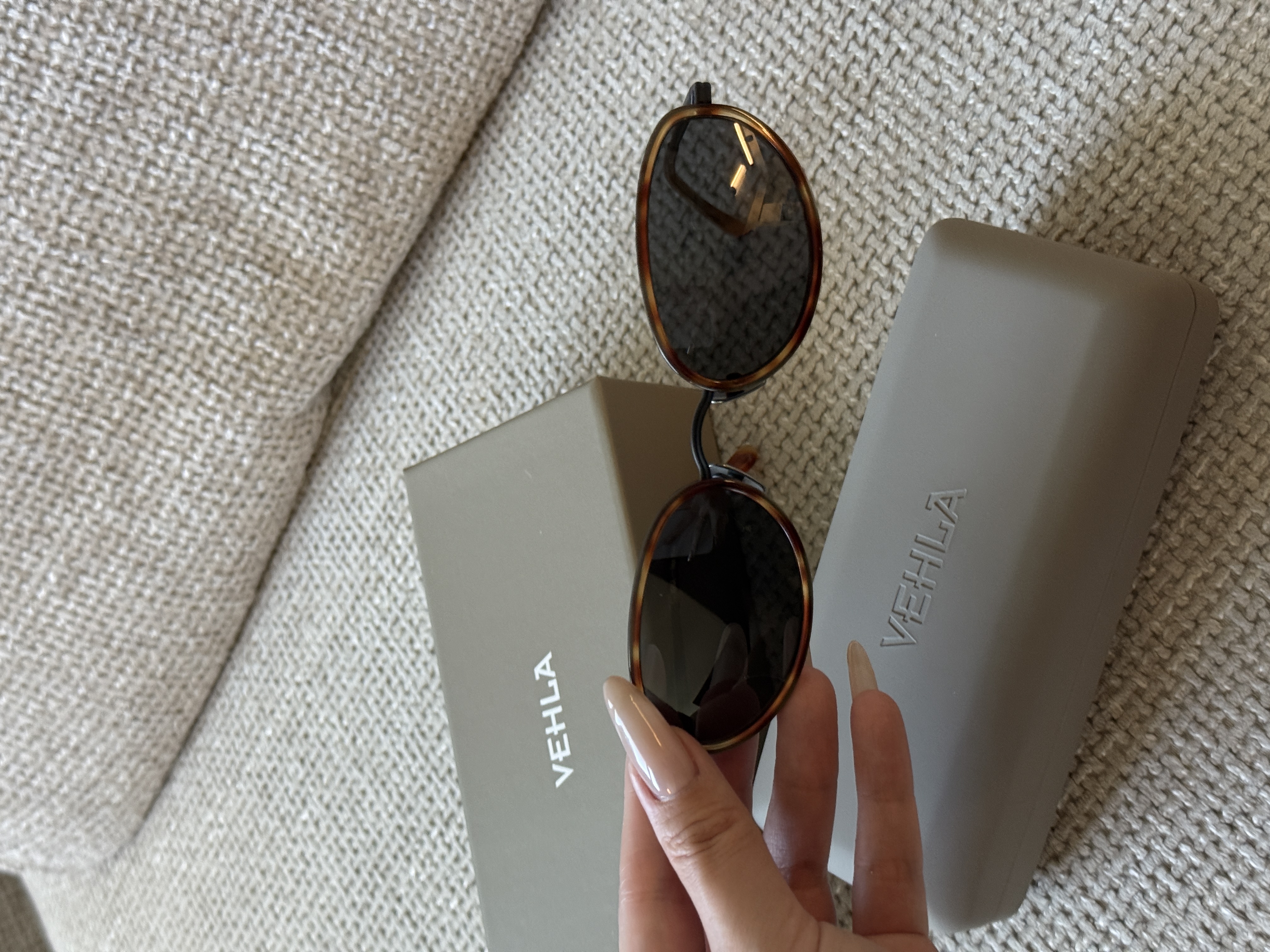 Vehla eyewear held with grey cases on textured upholstery