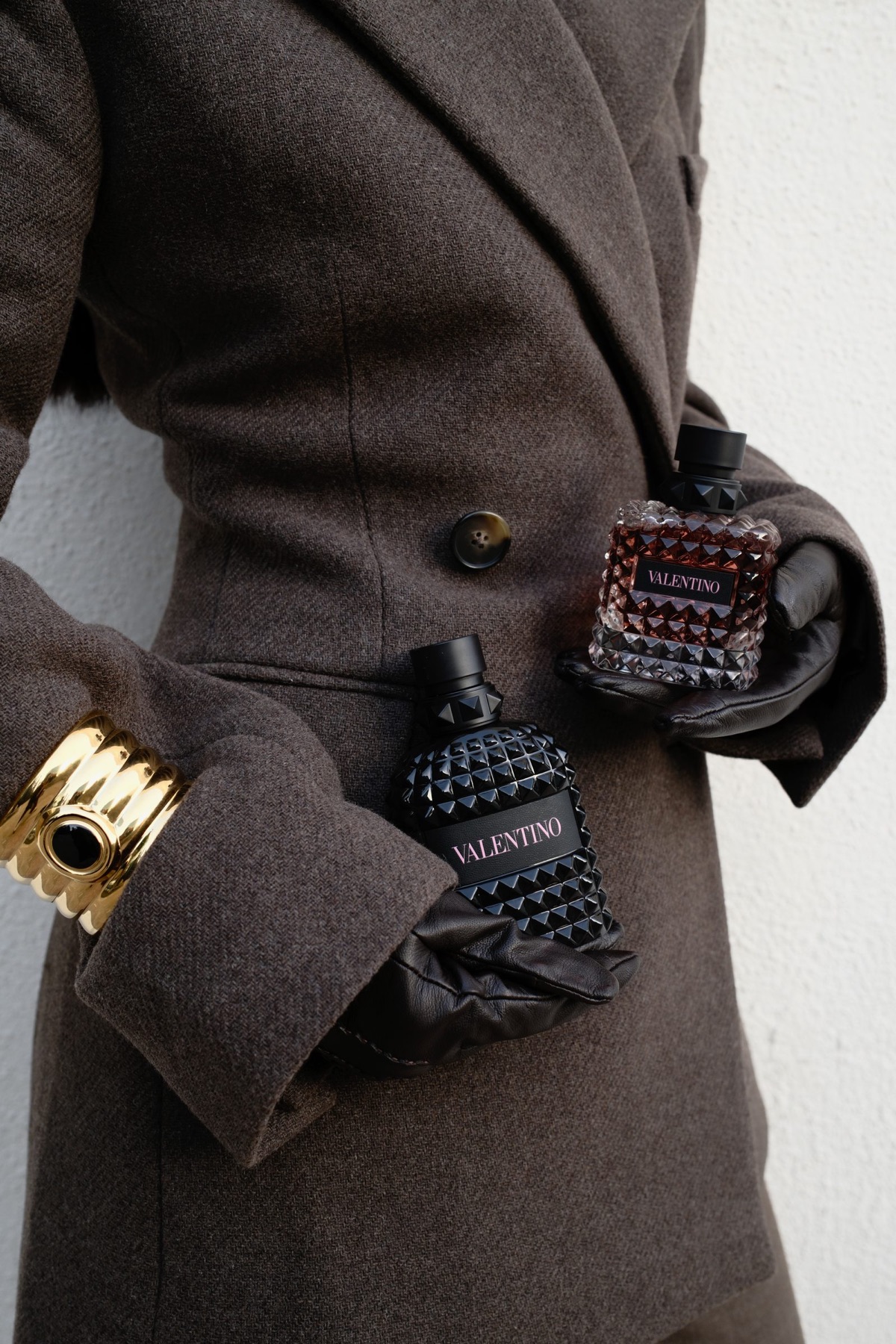 Valentino fragrance held against brown tailoring