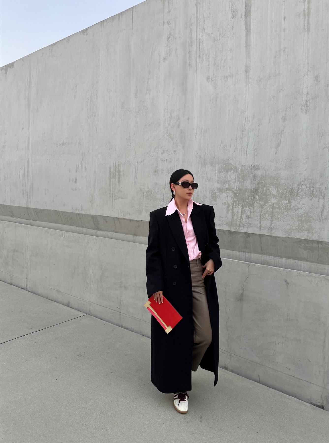 Neutral city styling against a concrete wall with a red folder